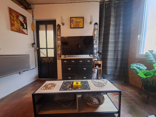 Salon moderne avec un téléviseur, un meuble bas et des décorations murales.