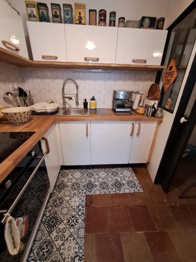 Cuisine moderne avec un plan de travail en bois et un sol carrelé décoratif