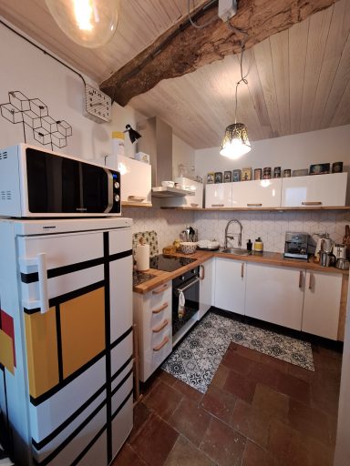Cuisine moderne avec un réfrigérateur décoré, équipement complet et décor chaleureux.