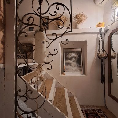 Escalier en bois avec balustrade décorative, mur avec des motifs et accessoires artistiques.