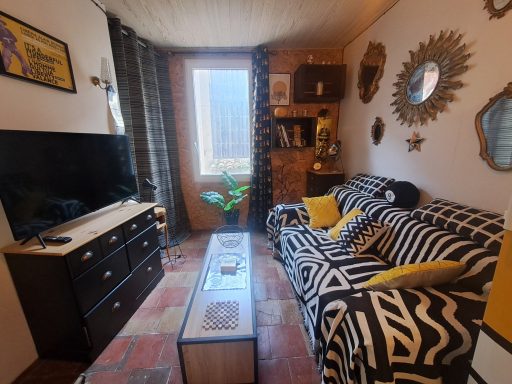 Salon lumineux avec canapé rayé, télévision et décor chaleureux.
