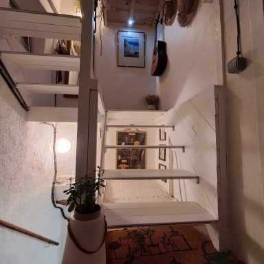 Escalier avec un mur blanc, une plante en pot et des éléments décoratifs.