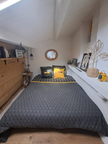 Chambre avec lit en noir et or, décorée de meubles en bois et miroirs.