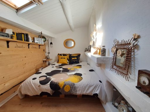 Chambre lumineuse avec un lit confortable, décorée de coussins et d'objets rétro.